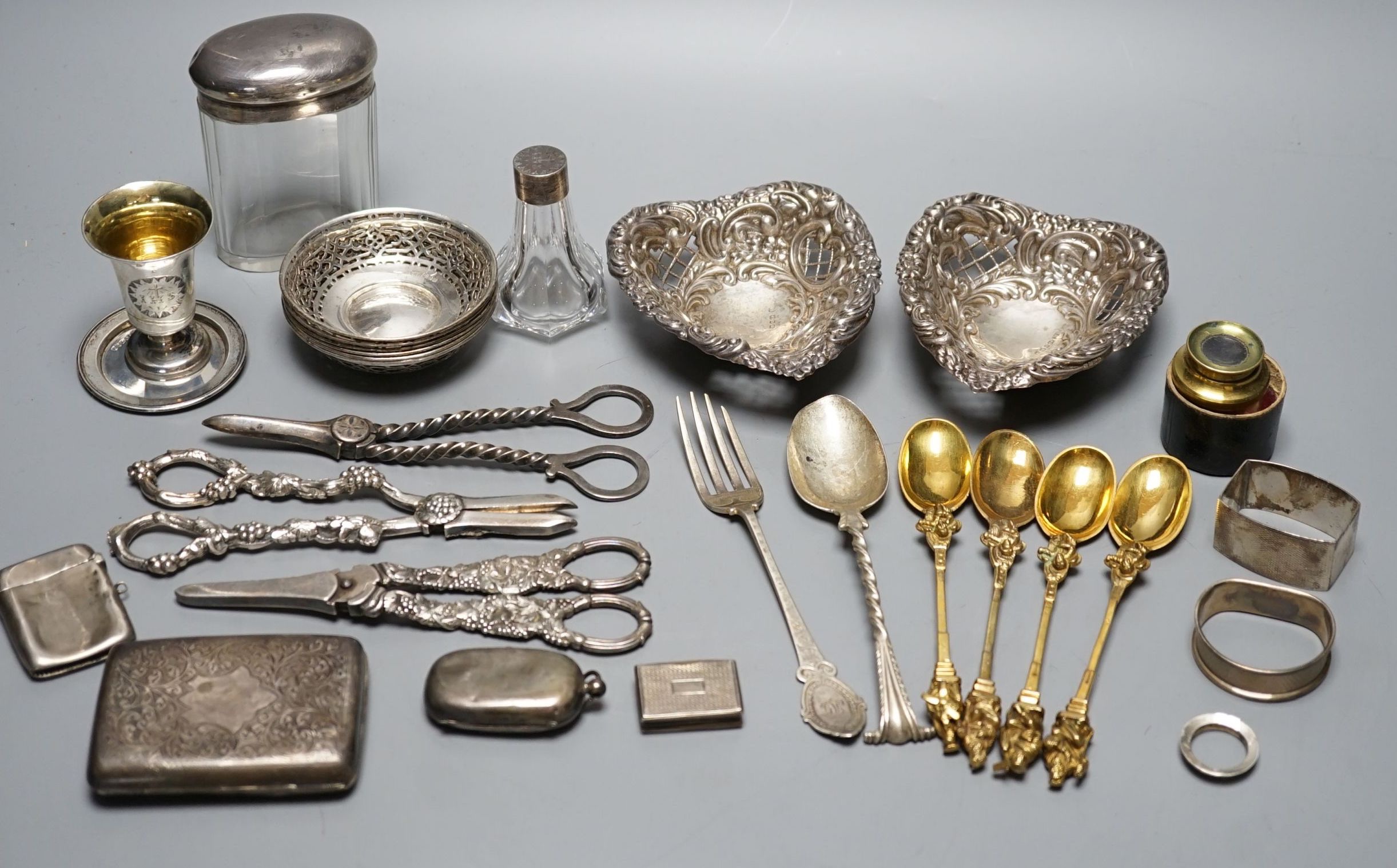 A cased Victorian silver part communion set, a silver cigarette case, two silver napkin rings, a set of five pierced silver bonbon dishes, a pair of Victorian silver grape shears, Georgian silver vinaigrette, pair of sil